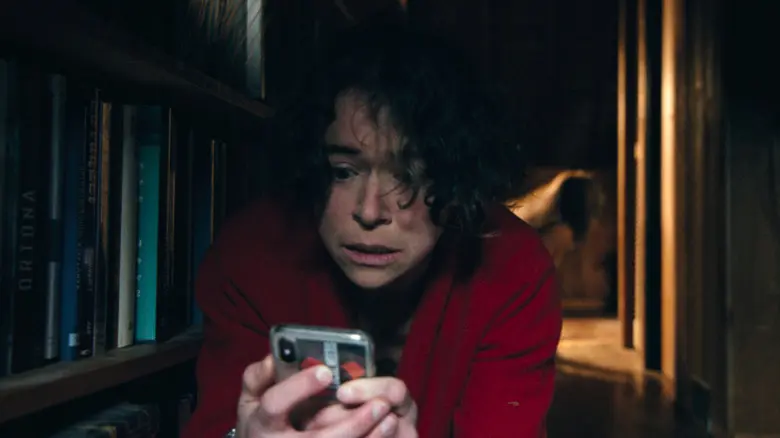 لیز سعی می‌کند با گوشی‌اش کار کند، در حالی که موجودی پشت سر او در فیلم «Keeper» مخفی شده است