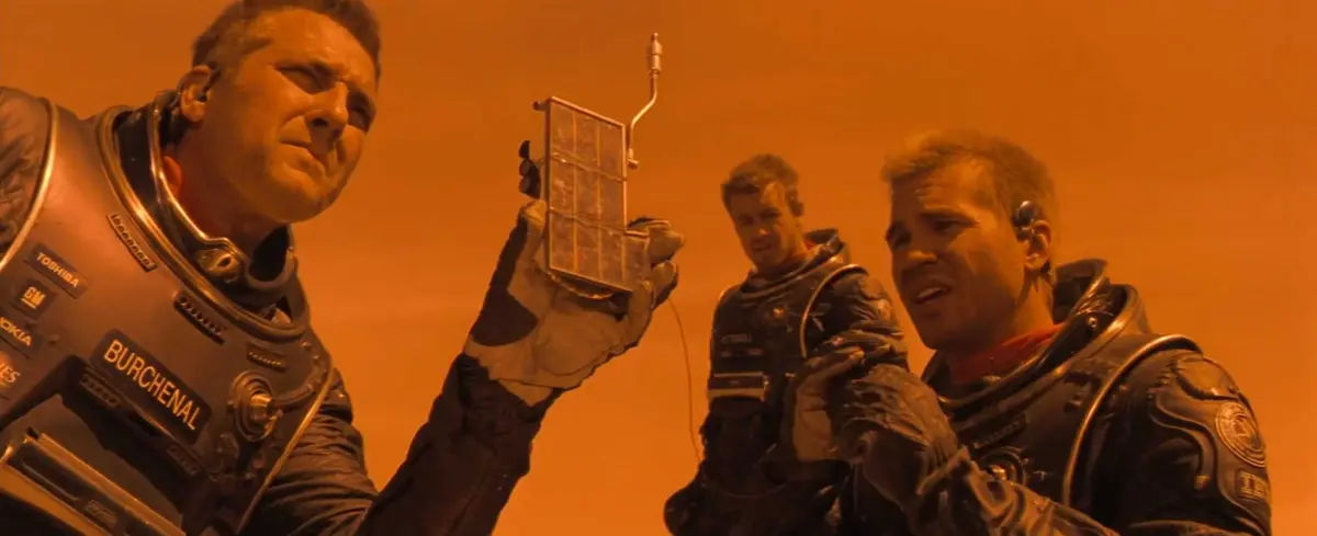 در صحنه‌ای از فیلم «سیاره سرخ»، دانشمندانی که توسط تام سیز‌موره، سایمون بیکر و وال کیلمِر به عهده‌شان سپرده شده‌اند، به خسارات پایگاه خود روی مریخ می‌نگرند.