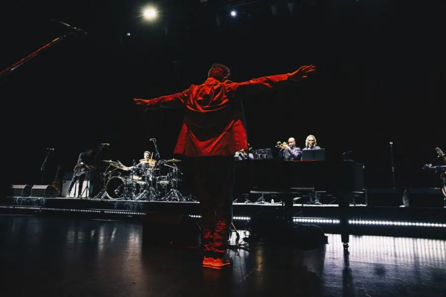 خواننده‌ای در صحنه جلوی جمعیتی که دستشان را بالا برده‌اند.