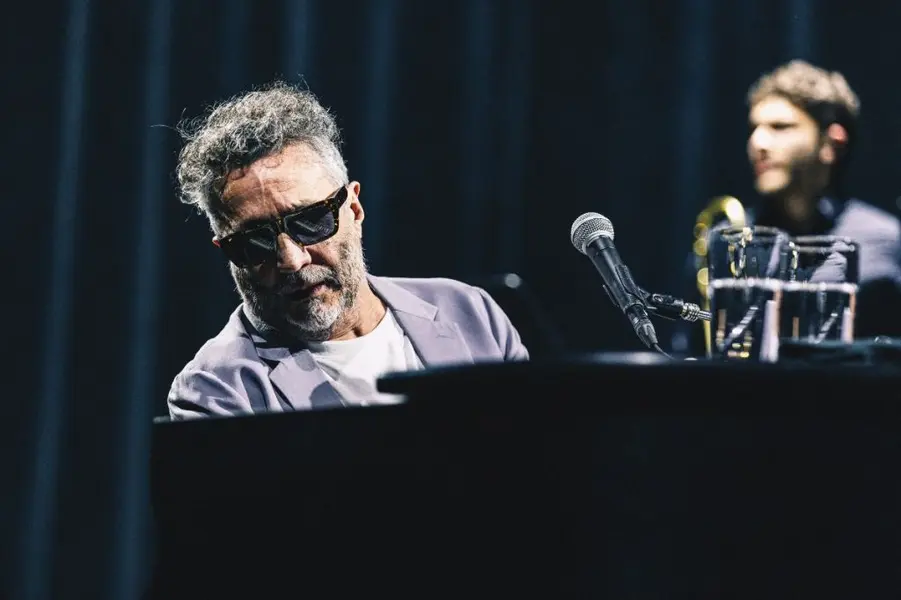 مردی با عینک آفتابی در حال نواختن پیانو.